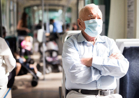 Elderly man in mask sitting in tram