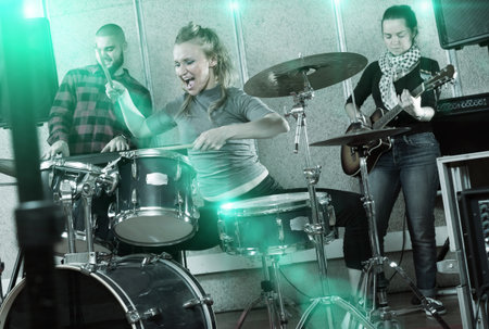 Rehearsal of music group with female drummer