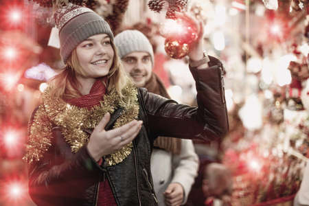 Positive young couple buying decoration at Christmas Fairの写真素材