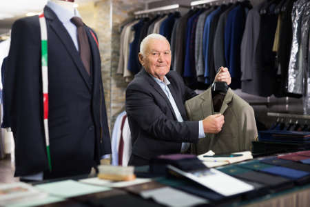 Mature man chooses fashionable jacket in clothing storeの写真素材