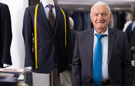 Portrait of successful elderly man tailor in his sewing workshop