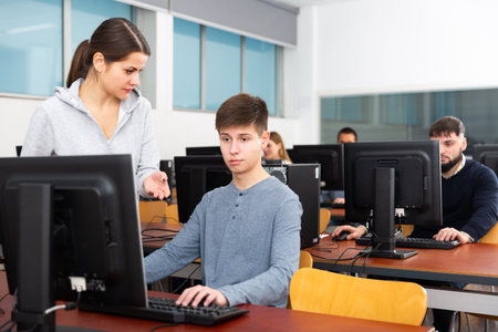 Adult female teacher helping male studentの写真素材