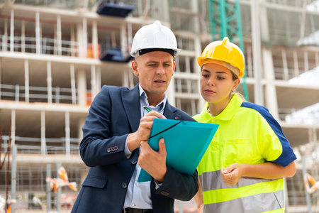 Civil engineer and a young woman worker discuss a construction plan