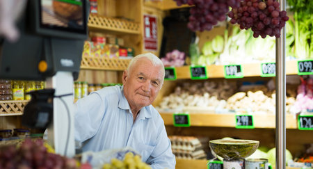 Portrait of a positive male salesperson at the checkout counter at grocery supermarket