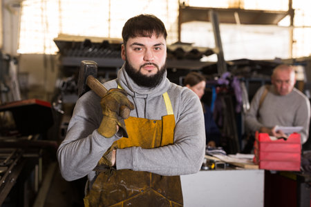 Man mechanic working with hand hammer in workshopの写真素材