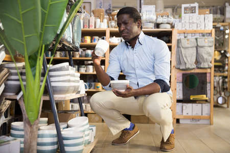 African American choosing ceramic tea cup in tableware storeの写真素材
