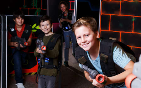 boy aiming laser gun at other players during lasertag gameの写真素材