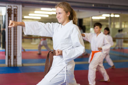 Girl in kimono posing during karate group trainingの写真素材