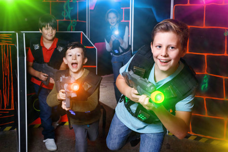 Portrait of preteen boy with laser gun having fun on dark lasertの写真素材