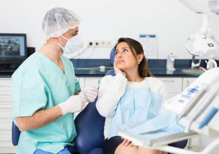Woman complains of toothache to dentistの写真素材