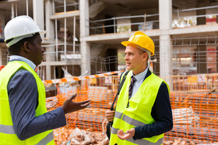 Two engineers standing on construction site and talking
