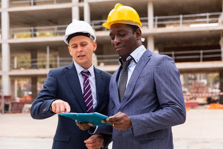 Two successful architects are discussing the construction plan
