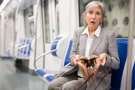 Mature woman amazed by theft from her bag in subway carの写真素材
