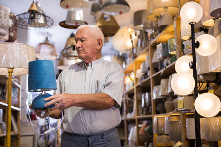 Mature man choosing table lamp at storeの写真素材