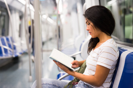 Oriental woman reading book in metropolitan trainの写真素材