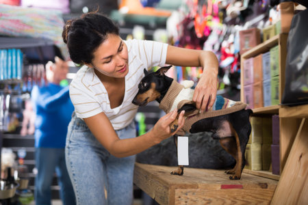 Woman dressing her dog in pet shop