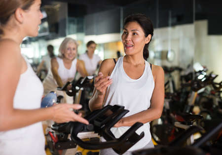 Two women warming up on bikes in gymの写真素材