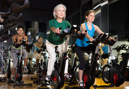 Women exercising on stationary bikes at gym