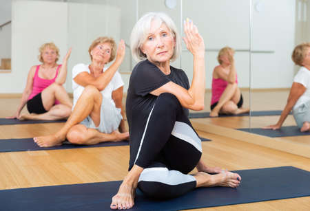 Elderly women posing in the pose of the lord of the fish Ardha Matsyendrasanの写真素材