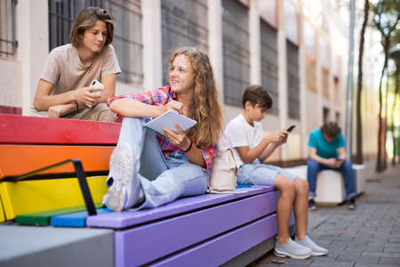 Schoolchildren sitting on bench in schoolyardの写真素材