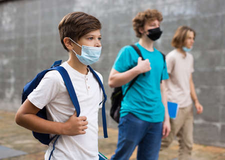 Teen boy in protective mask walk along summer street after finishing college lessons closeupの写真素材