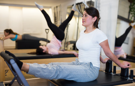 Young Latina practicing pilates on reformer at gymの写真素材