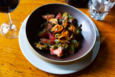 Tomatoes with pesto, mussels, olives and capersの写真素材