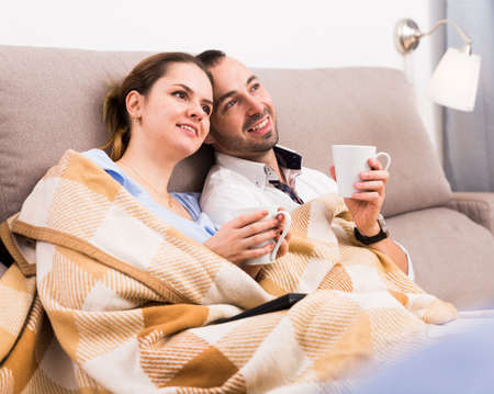 Couple is watching TV on the sofaの写真素材