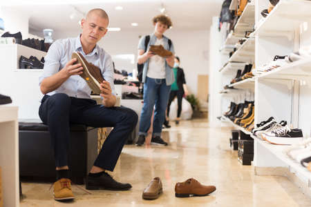 Man trying on suede and leather loafers in storeの写真素材