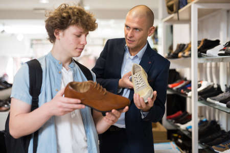 Teenager with the help of sales assistant selects summer shoesの写真素材