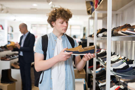 Teenager chooses moccasins on the shelves of shoe storeの写真素材
