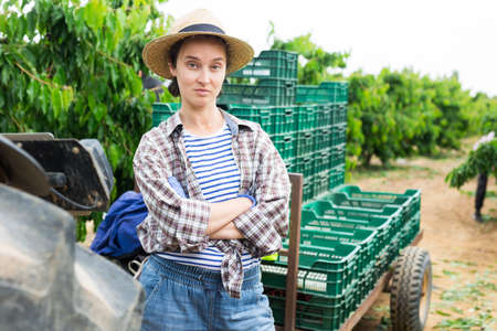 Female farmer posing near tractor on farmの写真素材