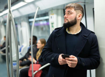 Young man with phone in subway carの写真素材