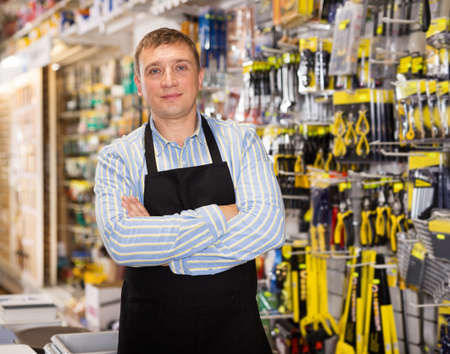 Man seller in apron having tools in handsの写真素材