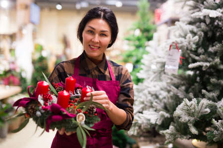 Portrait of a woman seller holding a Christmas composition with candlesの写真素材