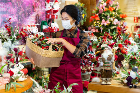 Asian saleswoman in mask selling Christmas decorationsの写真素材