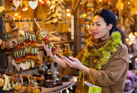 Asian female choosing decorations at Christmas fairの写真素材