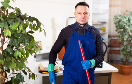 Man cleaner with mop standing in office