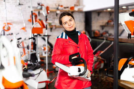 Woman with chainsaw in gardening tools storeの写真素材