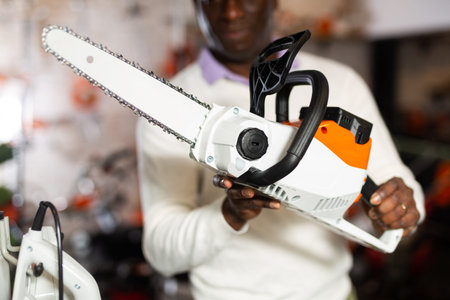 Man holding chainsaw in gardening tools store