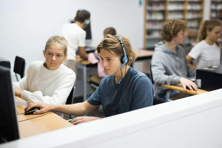 Teenage student in headphones at the computer in school classの写真素材