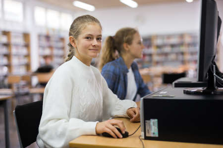 Teenager girls using computers in libraryの写真素材