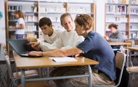 Teenage students working in groups in libraryの写真素材