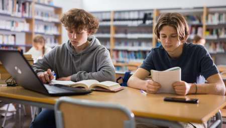 Teenage boys in libraryの写真素材