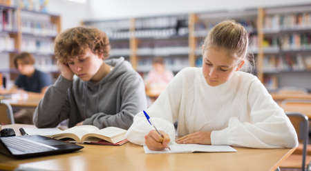 Girl and boy preparing for exams in libraryの写真素材