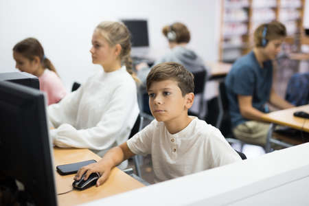 Preteen boy and girl learn to solve problems on computer in school classroomの写真素材