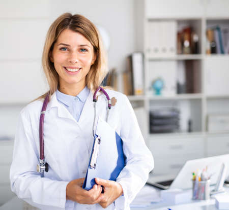 Positive woman doctor is standing with documentsの写真素材