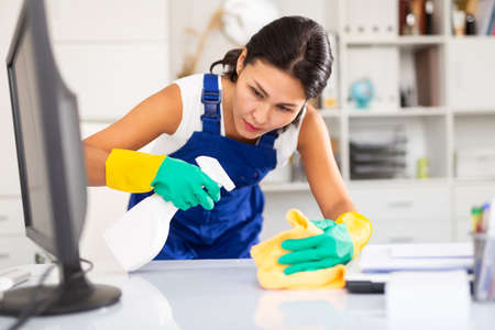 Kazhahstani woman wearing uniform cleaning at company officeの写真素材