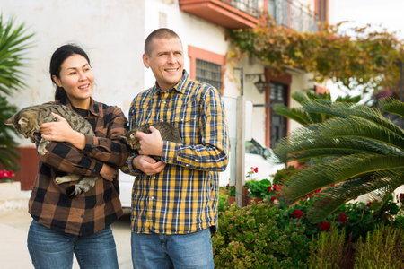 Smiling couple standing with cats near home