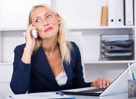 Mature woman talking on phone in office